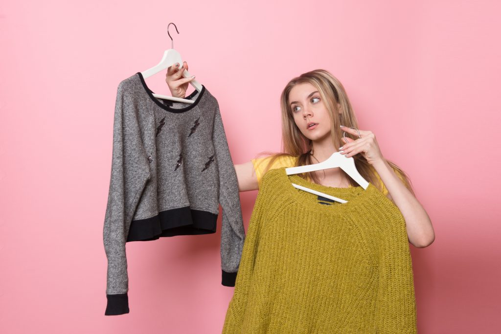 Woman choosing her fashion outfit. Girl thinking what to wear after the shopping.