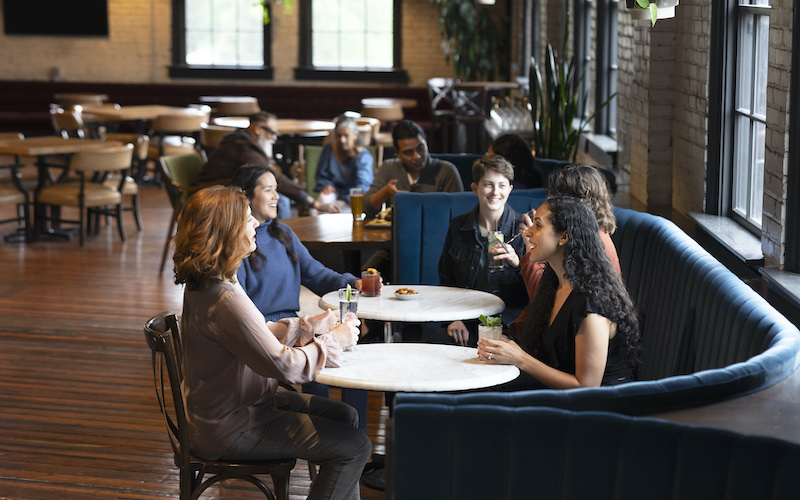 People drinking and socializing in a booth at The Monogram Lounge