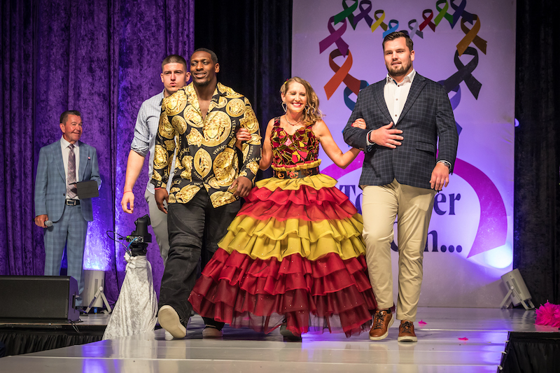 Kansas City Chiefs players escort a model/cancer survivor down the Bra Couture KC runway