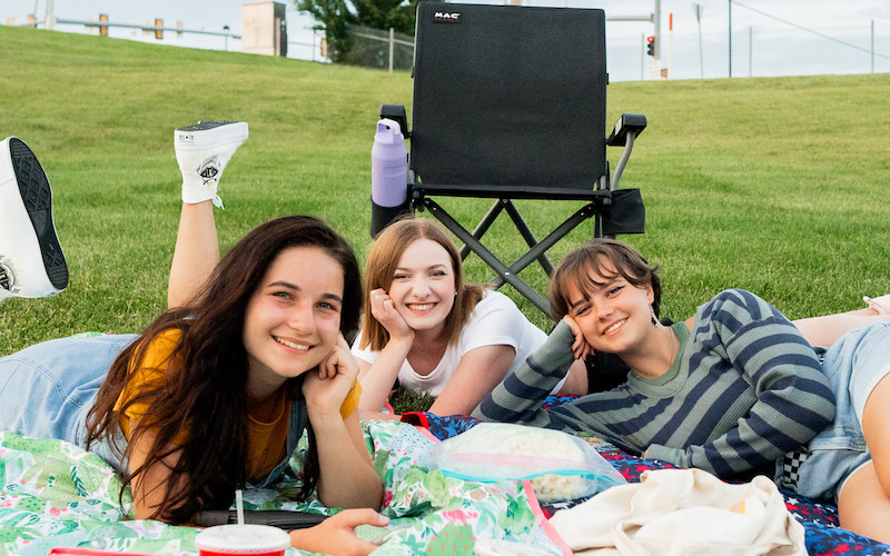 Three people picnicking in the grass at Bluhawk